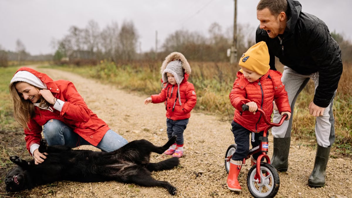 Happy family enjoying quality time outdoors with kids and dog in countryside.